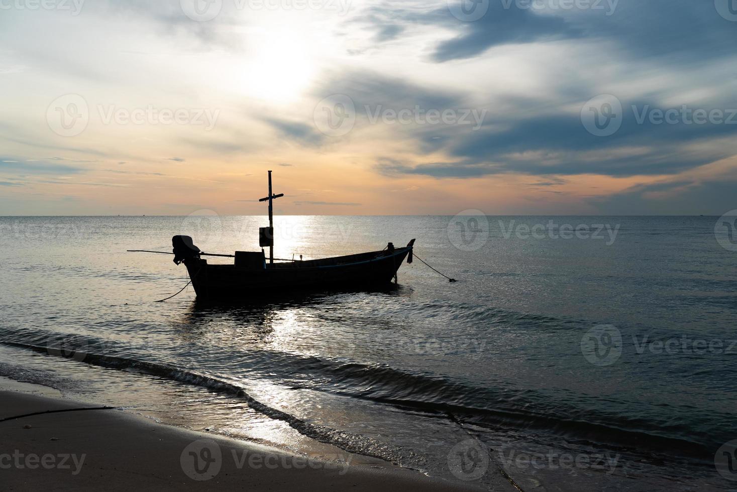 silhouette de petit bateau de pêche dans la mer au lever du soleil photo