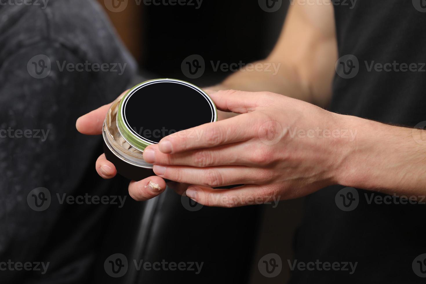 mains mâles tenant une crème avec un couvercle noir photo