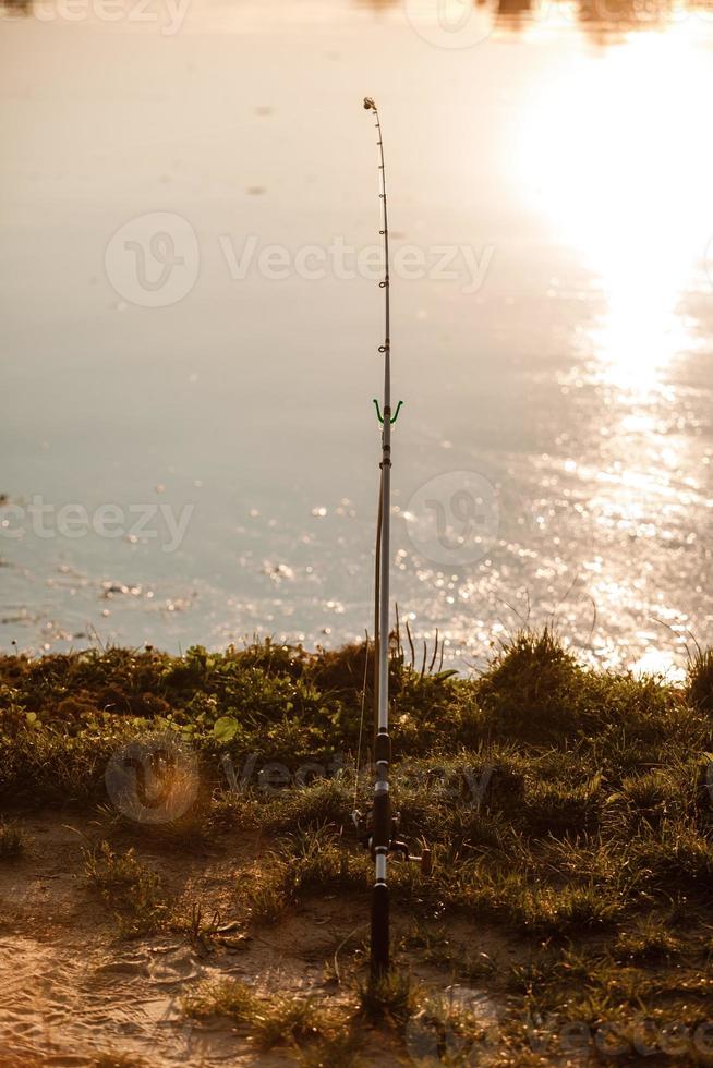 pêcheur avec canne à pêche au coucher du soleil photo