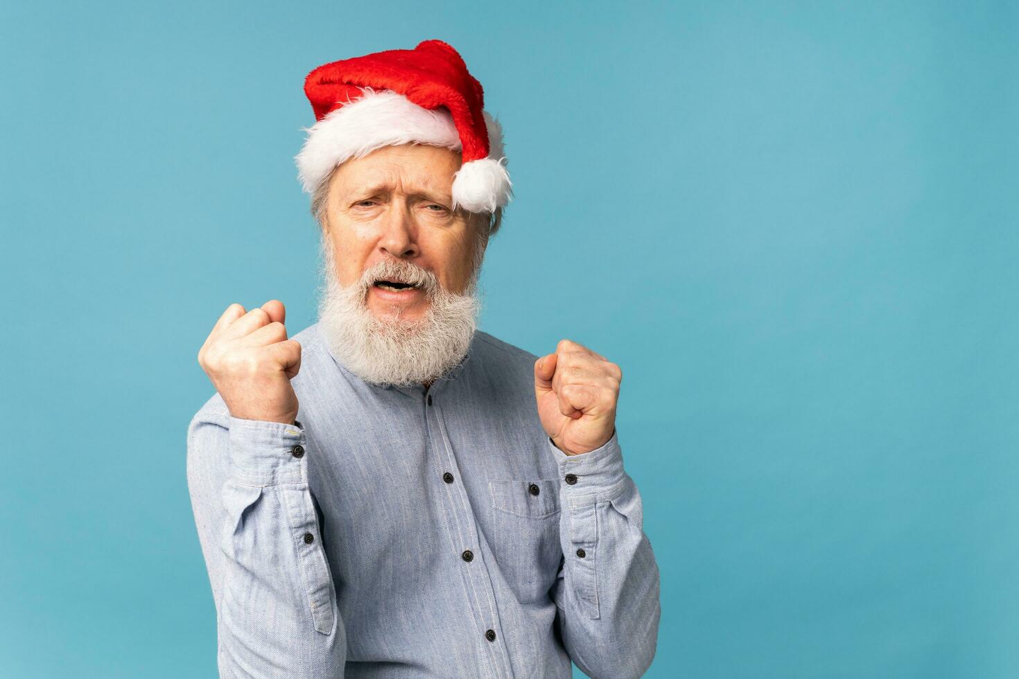 content sur de soi cool vieux barbu Père Noël claus gagnant élevage les poings célébrer triomphe et Succès plus de bleu Contexte avec copie espace photo