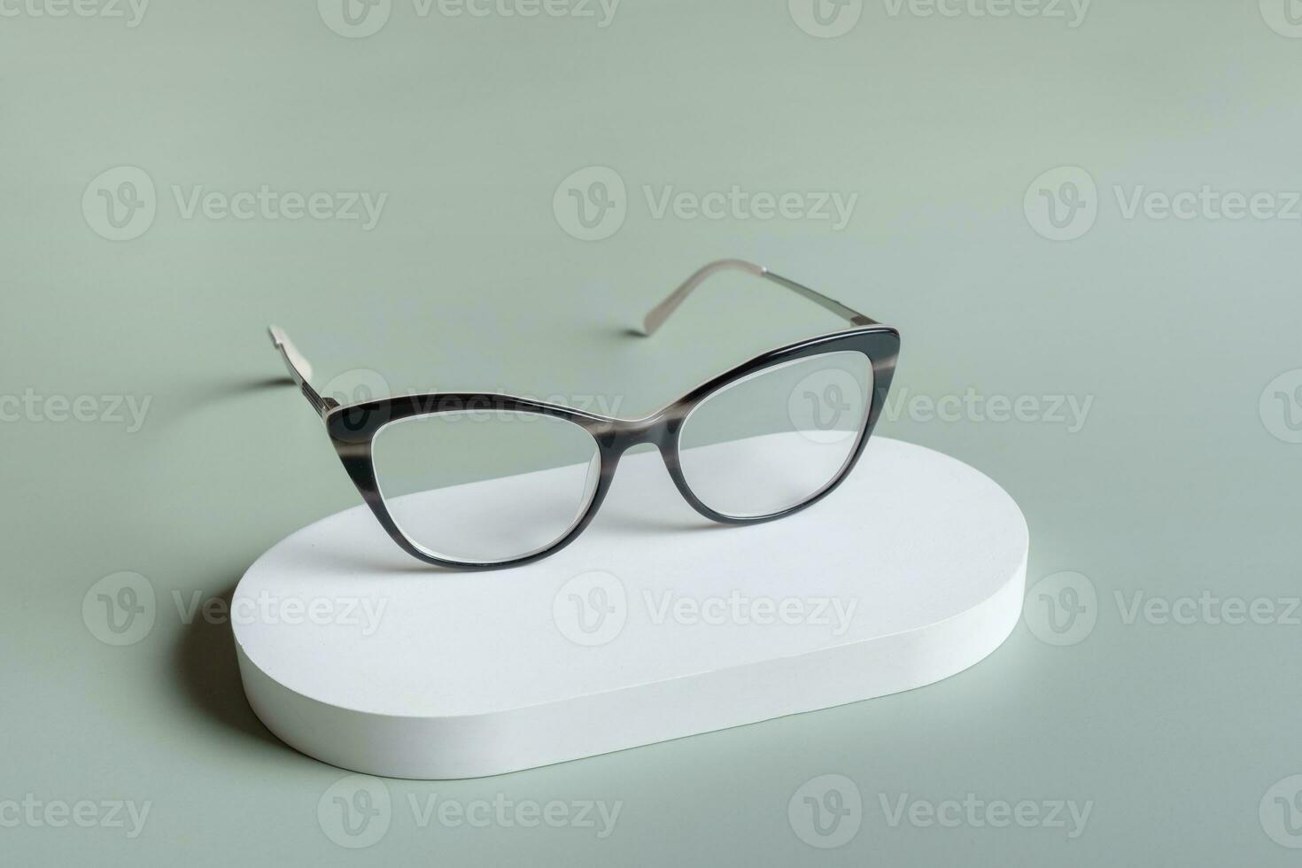 podium avec lunettes sur pastel vert Contexte. optique magasin, vision test, élégant des lunettes concept. photo
