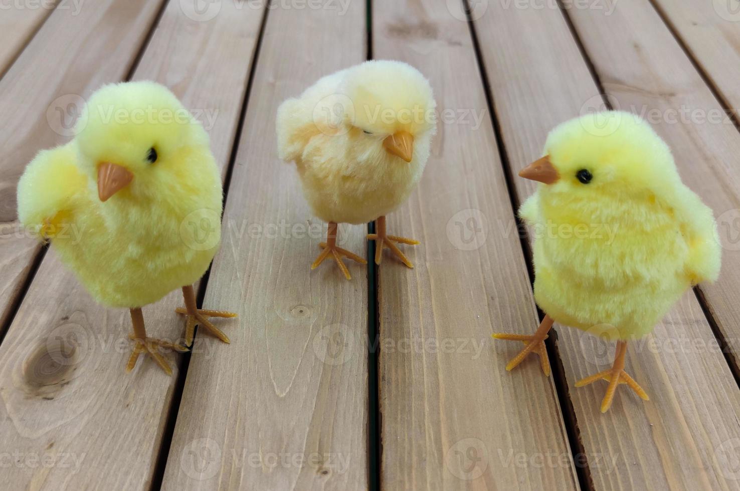 trois poulets jouets jaunes de pâques se tiennent sur les planches. photo