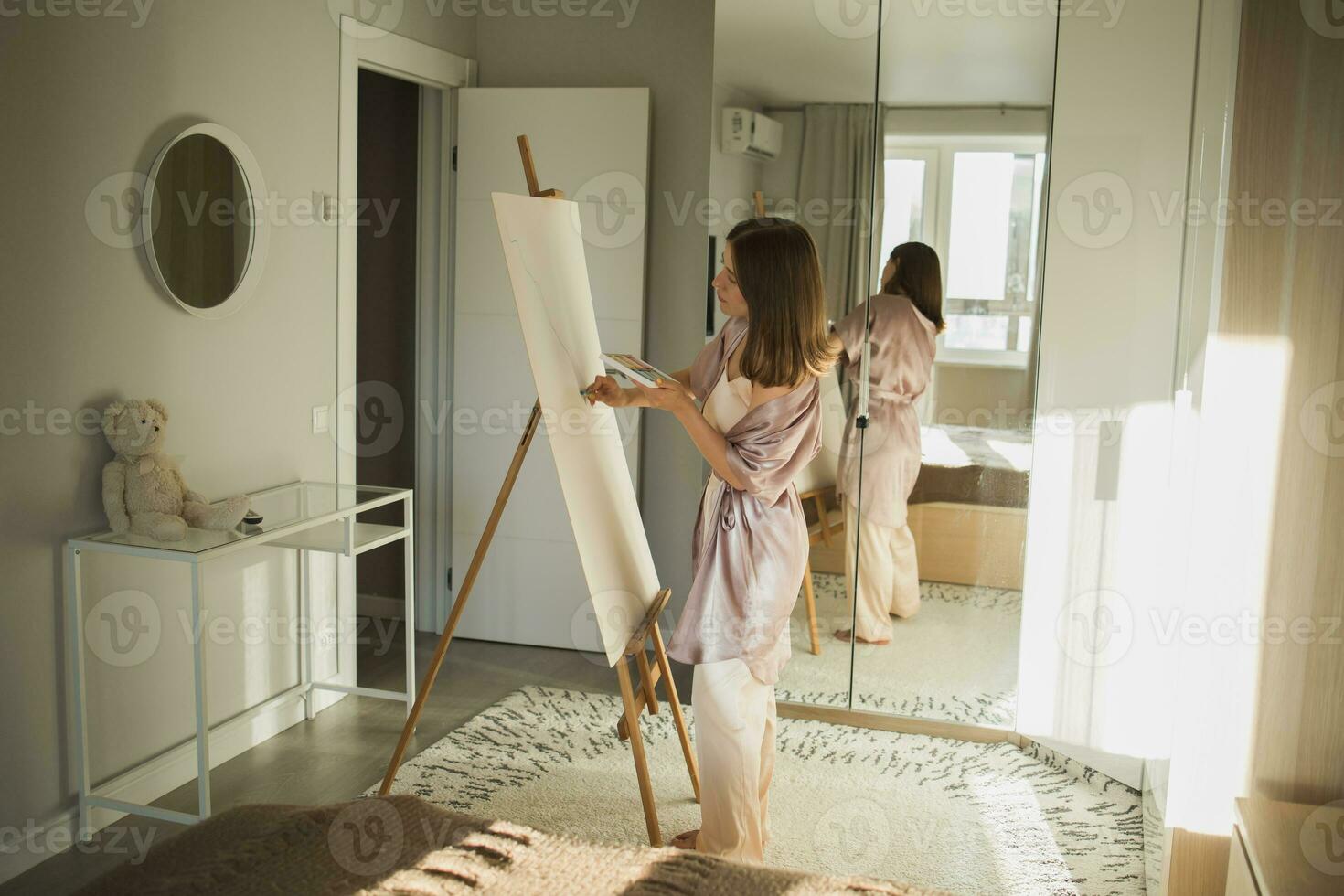 Jeune femme artiste La peinture sur Toile sur le chevalet à Accueil dans chambre - art et la créativité concept photo