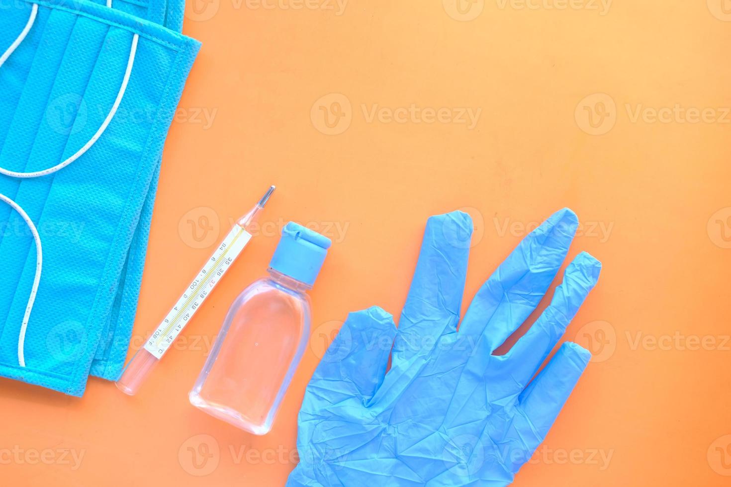 masques chirurgicaux, gants médicaux et désinfectant pour les mains sur fond orange photo