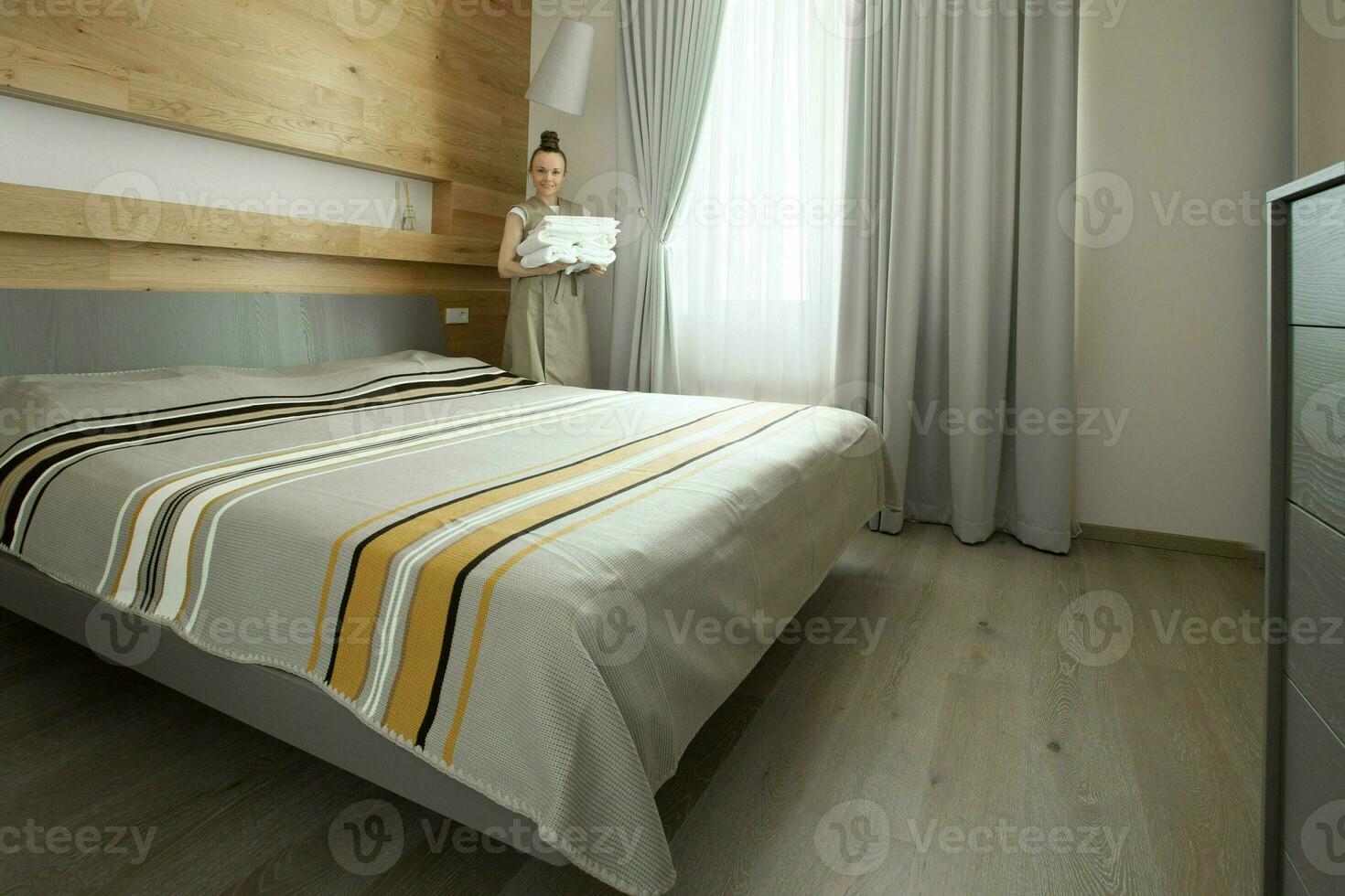 une femme permanent dans de face de une lit dans une chambre photo