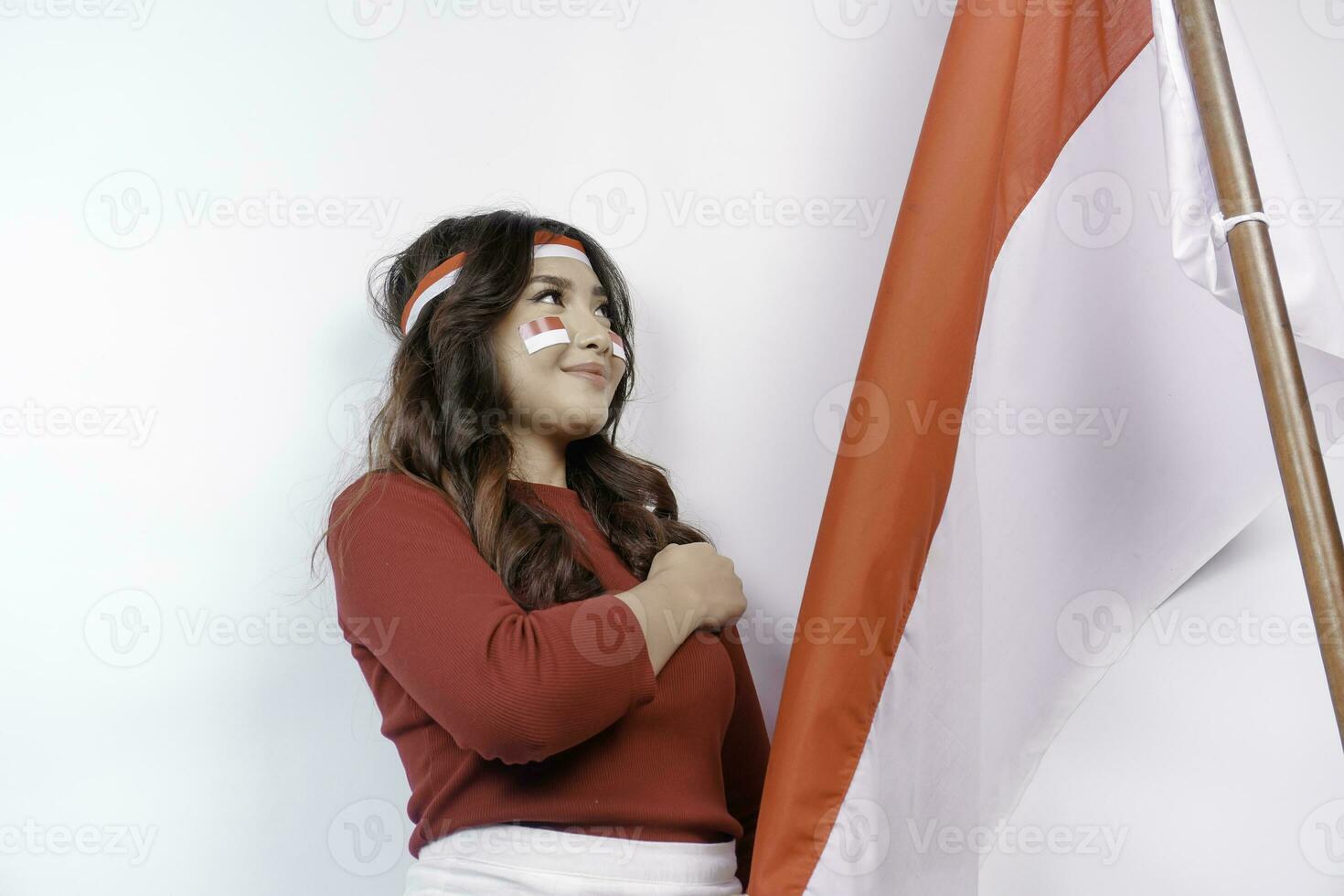 indonésien femme donner saluer avec fier geste tandis que en portant l'indonésie drapeau. l'indonésie indépendance journée concept. photo