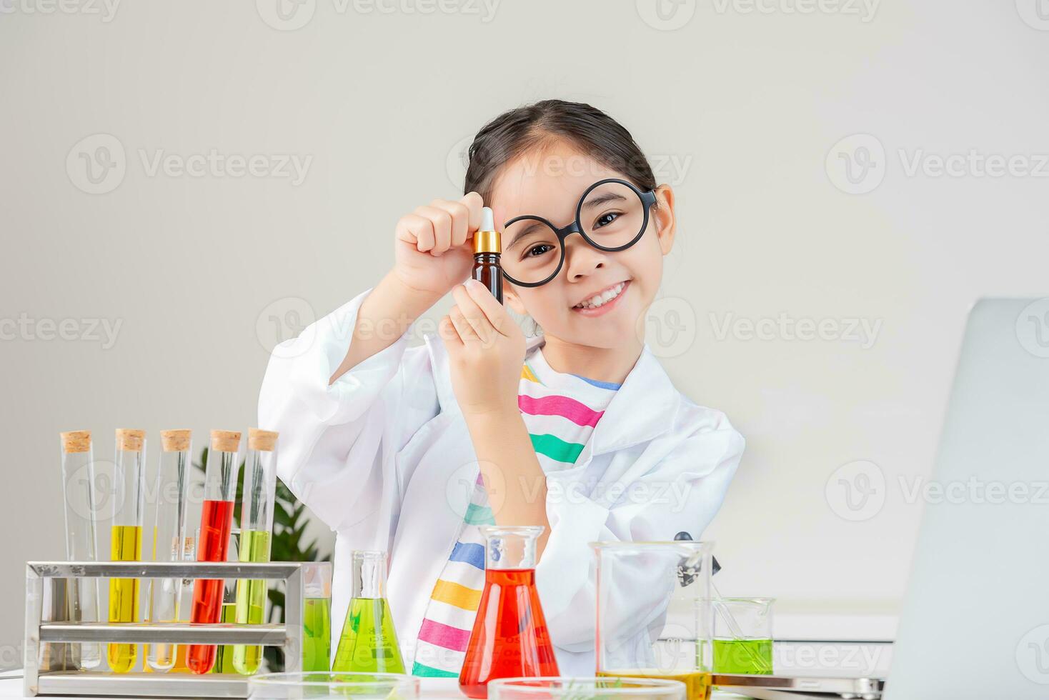 asiatique peu fille travail avec tester tube science expérience dans blanc salle de cours photo