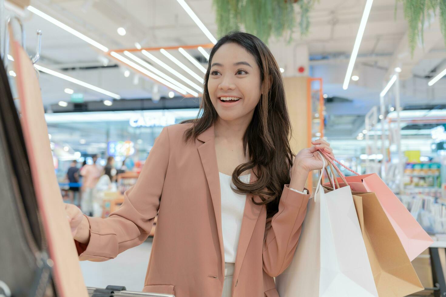 moderne content asiatique femelle mode de vie mode portrait. magnifique attrayant Jeune femme fille prendre plaisir élégant marcher avec achats sac paquets sur le rue, branché tenue sur achats centre commercial, Feuilleter produit photo