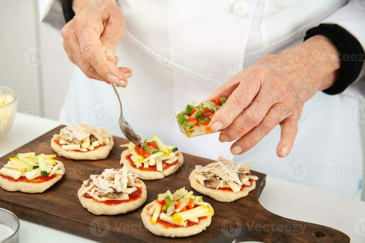 ajouter garnitures à le mini pizzas. ajouter des légumes. délicieux fait maison mini pizzas préparation. photo