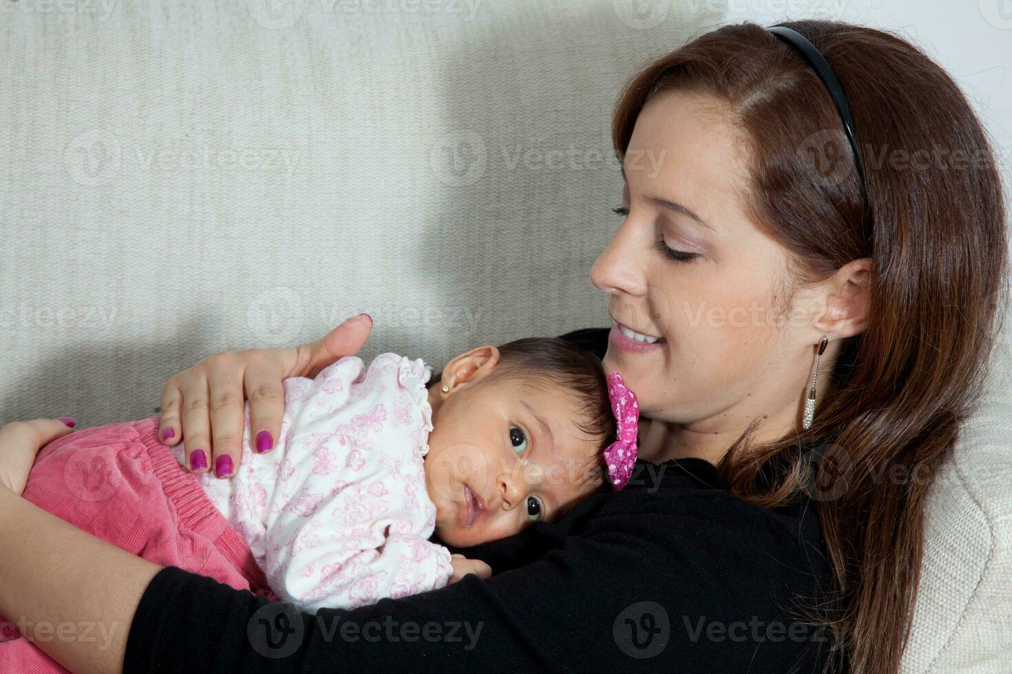 portrait de magnifique Jeune mère à Accueil avec sa un mois bébé fille. maternité concept. famille l'amour concept. photo