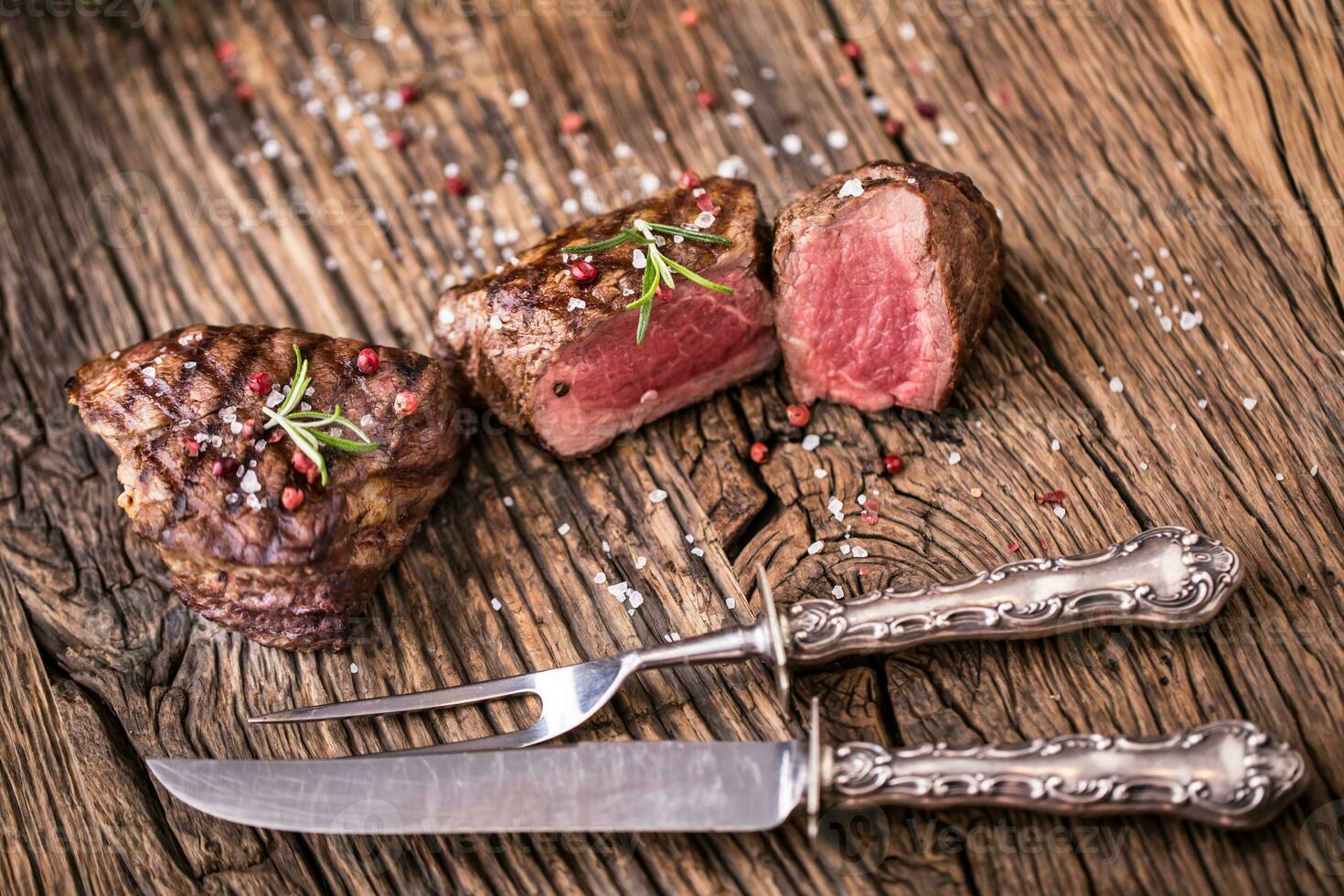 grillé du boeuf steak avec Romarin, sel et poivre sur vieux Coupe planche. du boeuf filet steak. photo