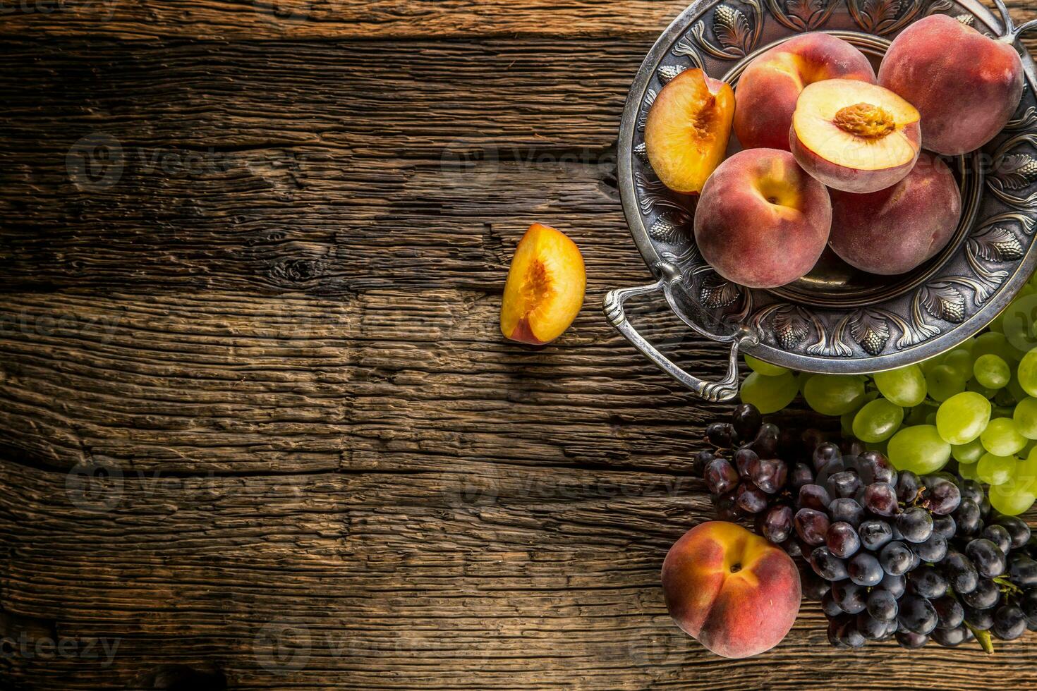 mûr les raisins et les pêches dans rustique bol et en bois table photo