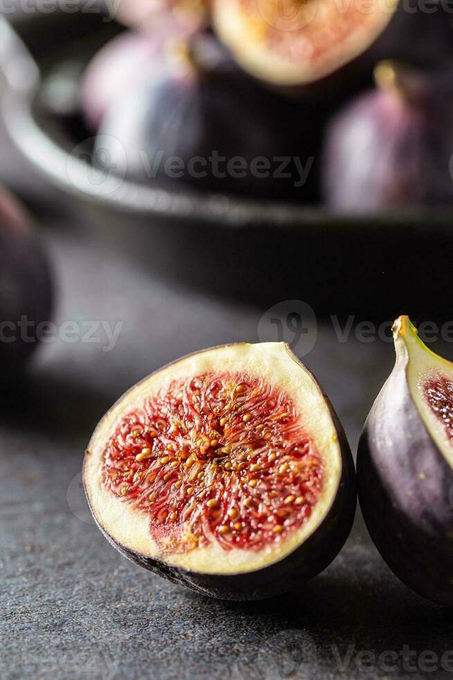 une peu figues dans une noir bol sur un foncé béton table photo