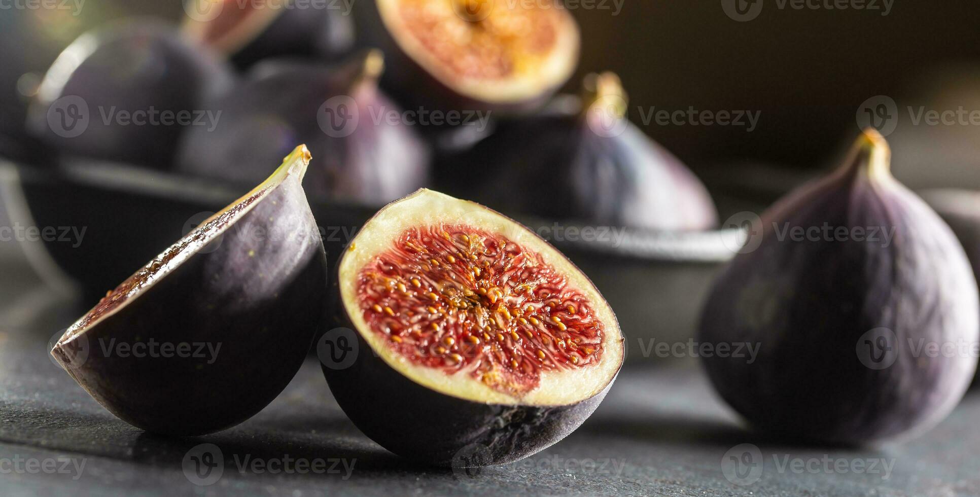 une peu figues dans une noir bol sur un foncé béton table photo