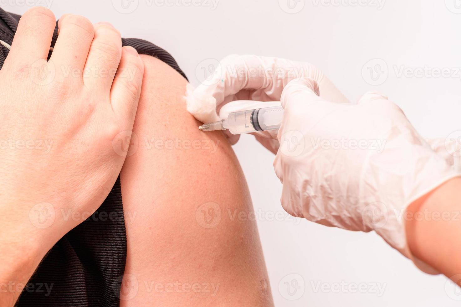 vaccination en gros plan, injection de vaccin à la main, médecin en gants blancs. photo