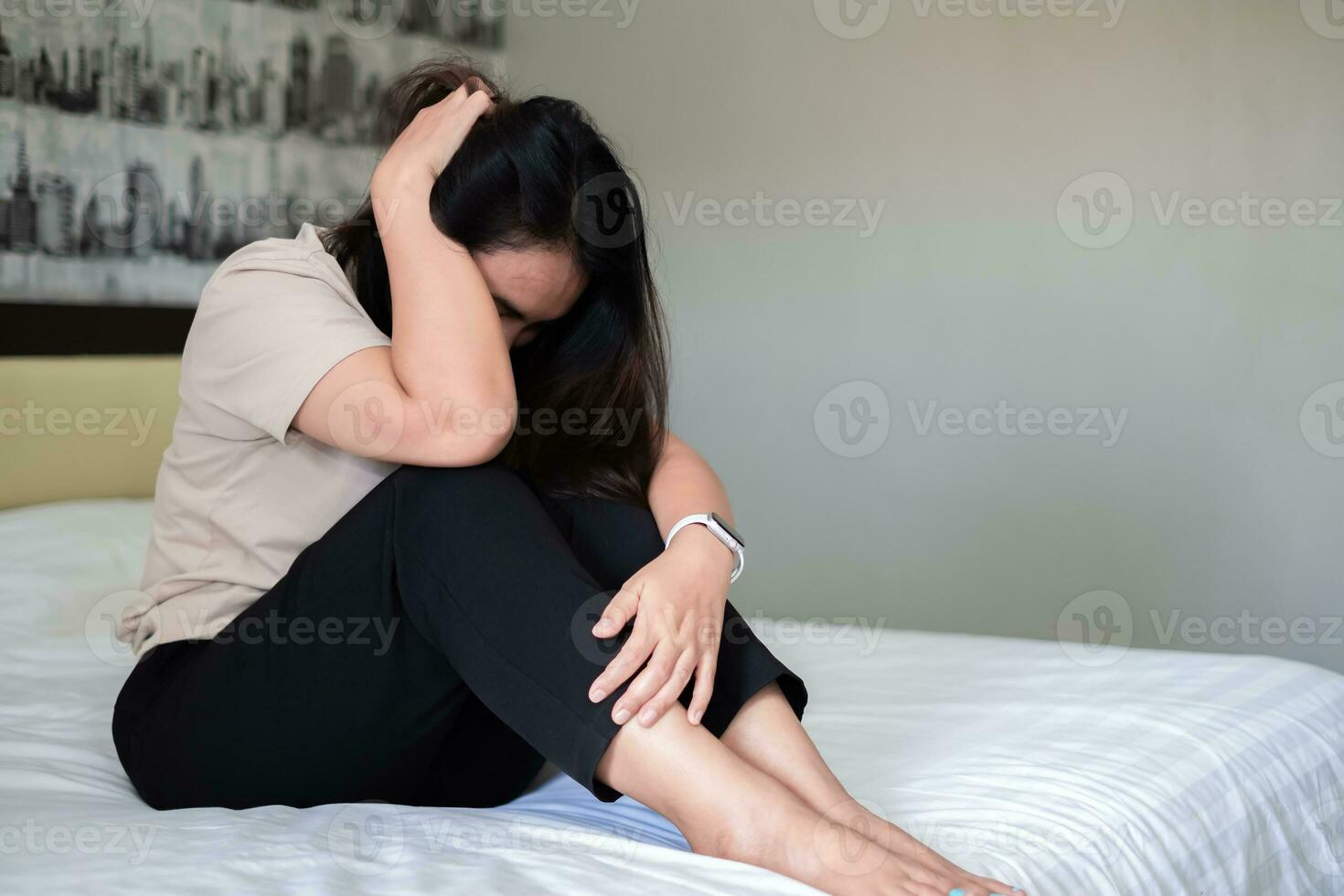 triste déprimé Asie femme Souffrance sur le blanc lit, elle est séance dans lit et émouvant sa front, sommeil désordre et stress concept photo