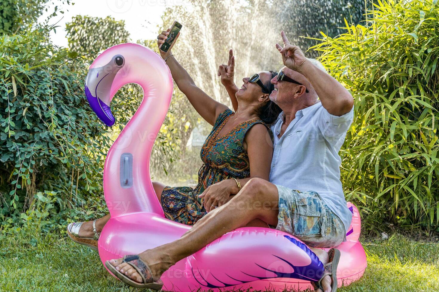 magnifique souriant milieu vieilli couple prise une selfie séance sur flamant gonflable jouet photo
