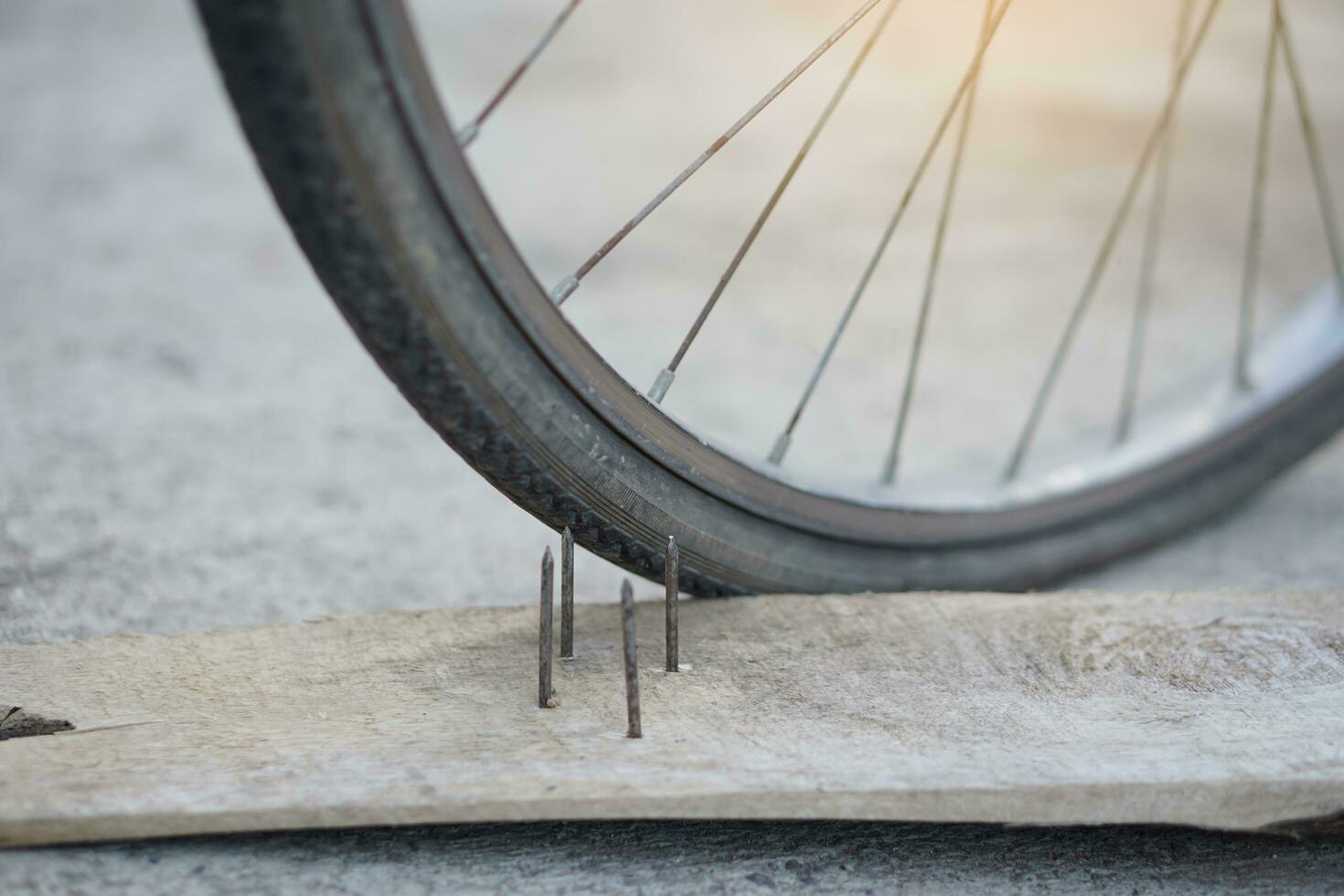 proche en haut ongles sur bois planche et plat vélo pneu. concept, peu sûr , dommage. être prudent et Regardez autour pendant cyclisme sur le sol ou risque lieux. accident pouvez être arrivé. photo