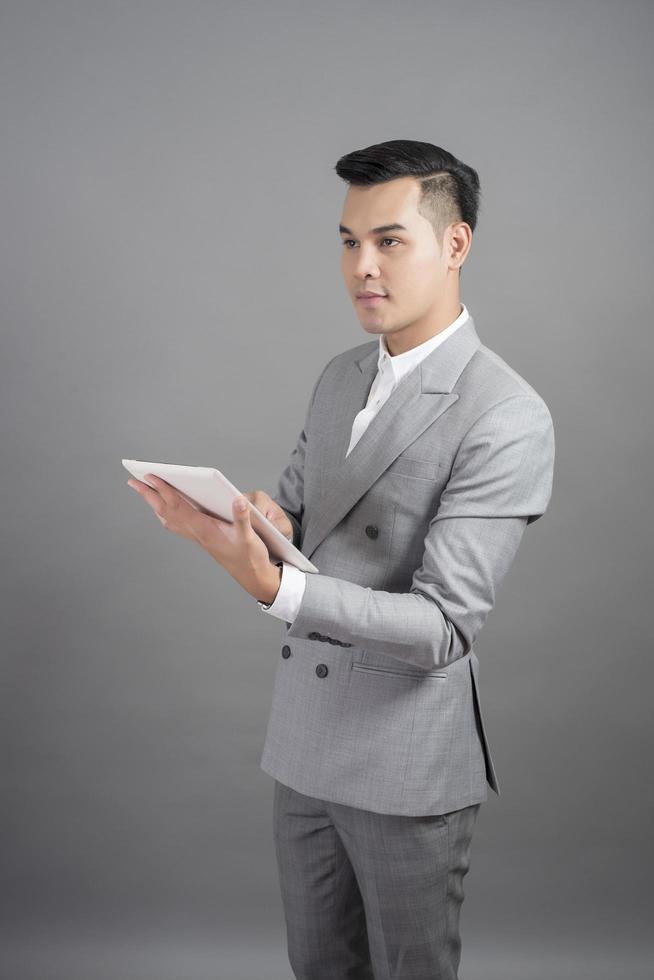 homme d'affaires utilise une tablette, portrait en arrière-plan gris studio photo