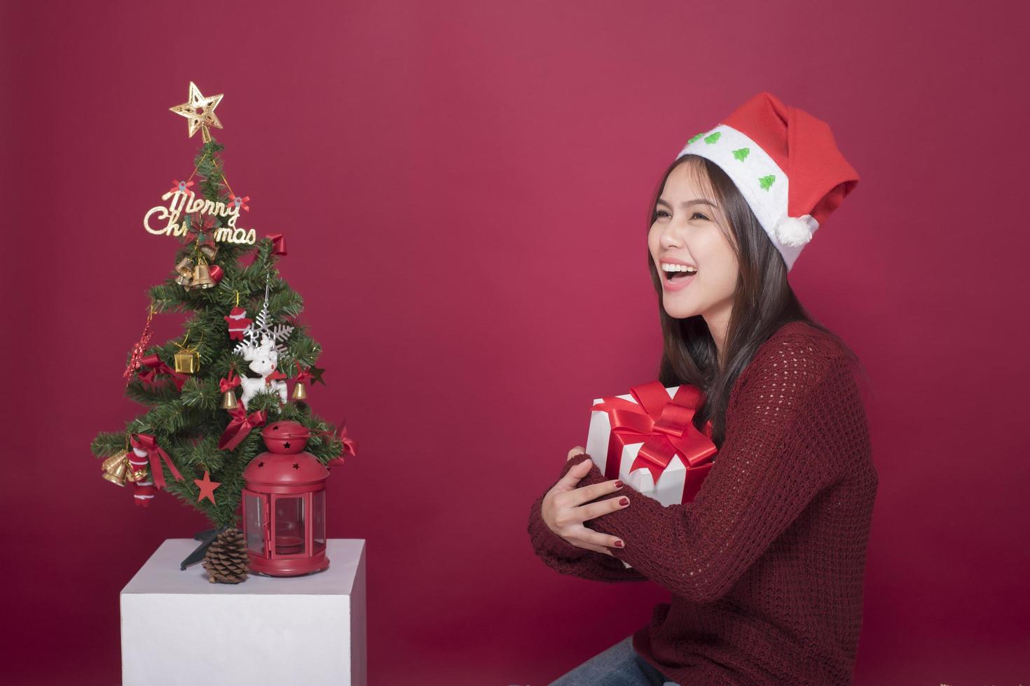 Belle fille du père noël en studio sur fond rouge, concept de noël photo