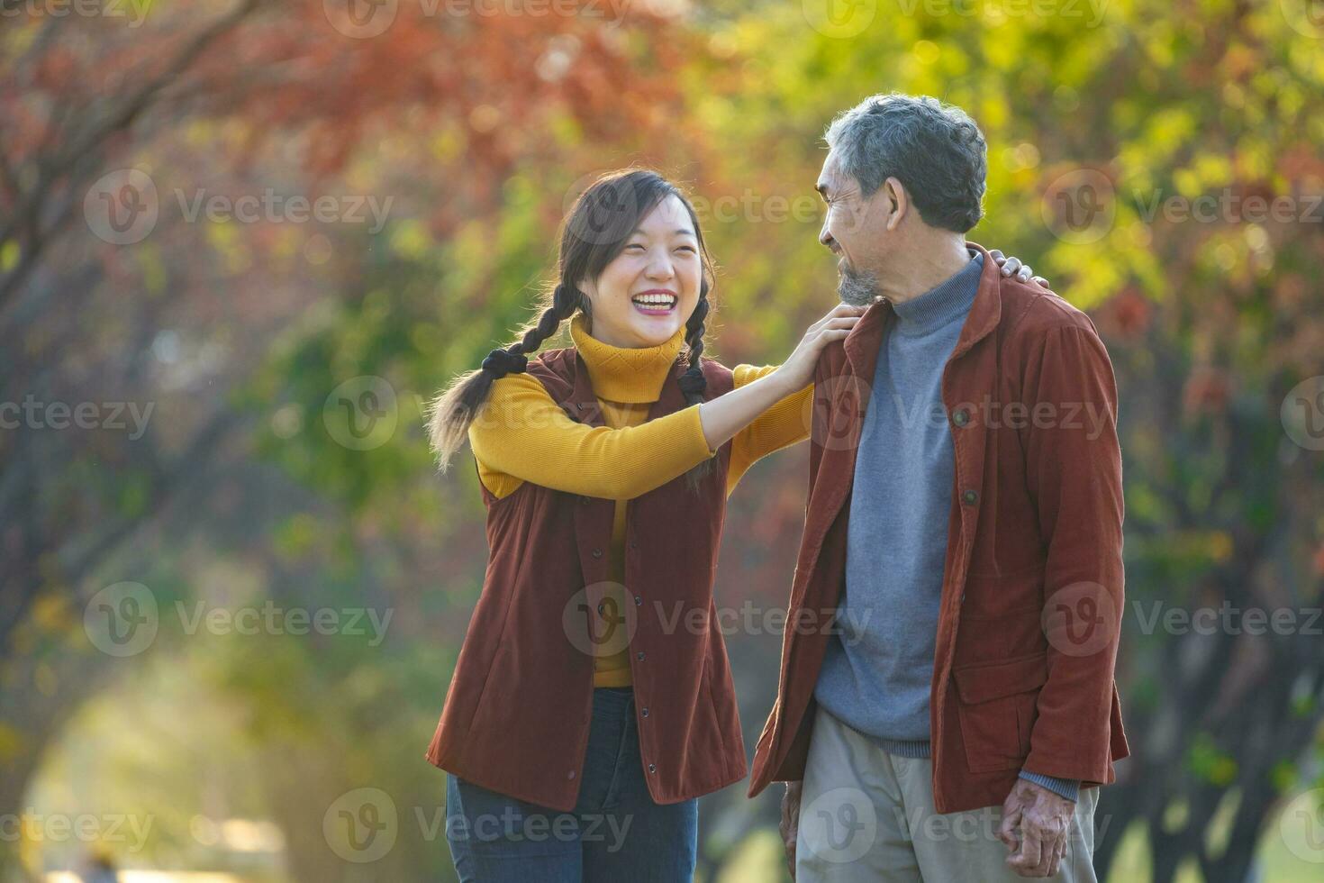 content asiatique famille en marchant ensemble dans le Publique parc pendant avec tomber Couleur de érable et ginkgo arbre pendant l'automne saison photo