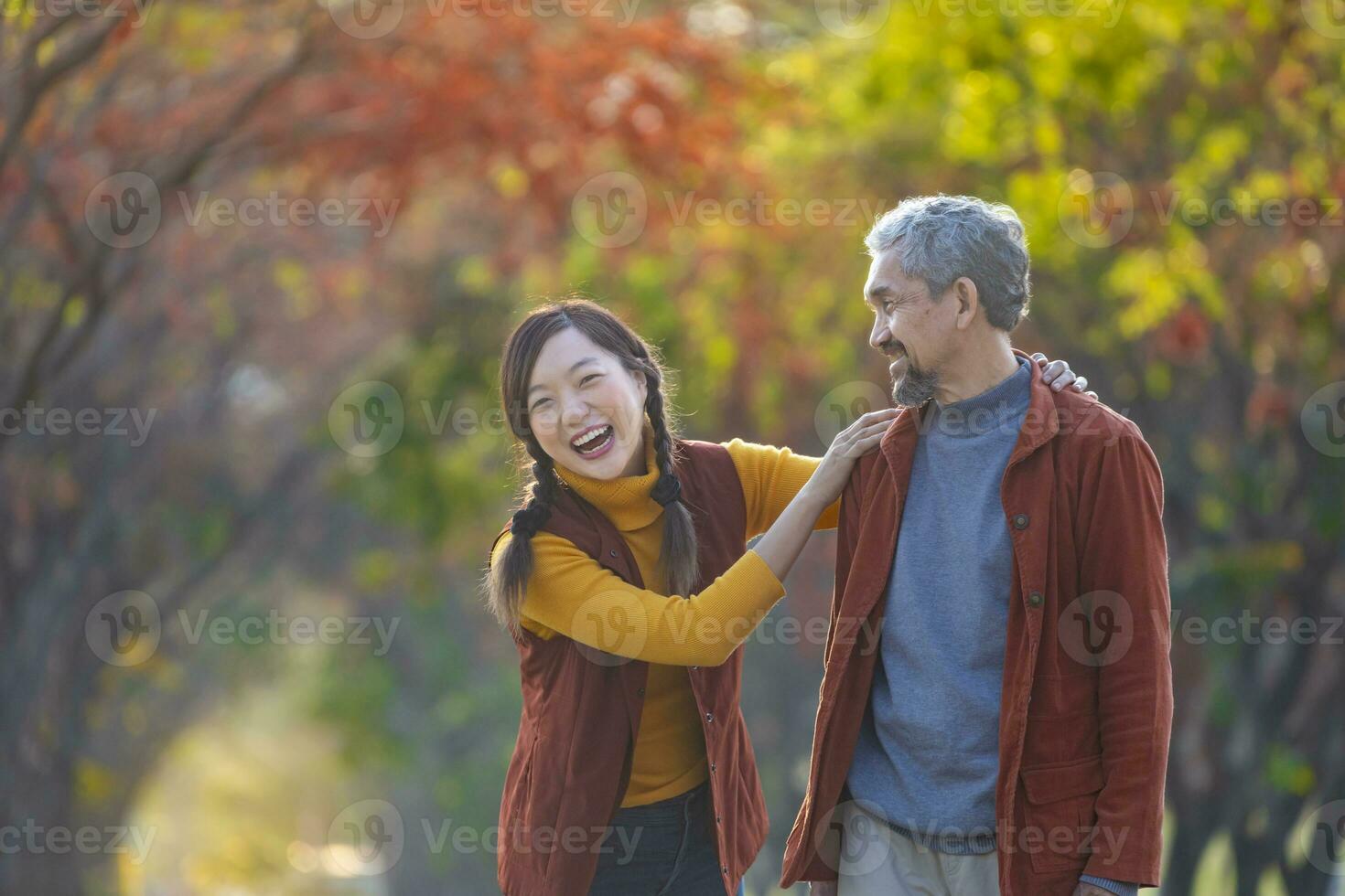 content asiatique famille en marchant ensemble dans le Publique parc pendant avec tomber Couleur de érable et ginkgo arbre pendant le l'automne saison photo