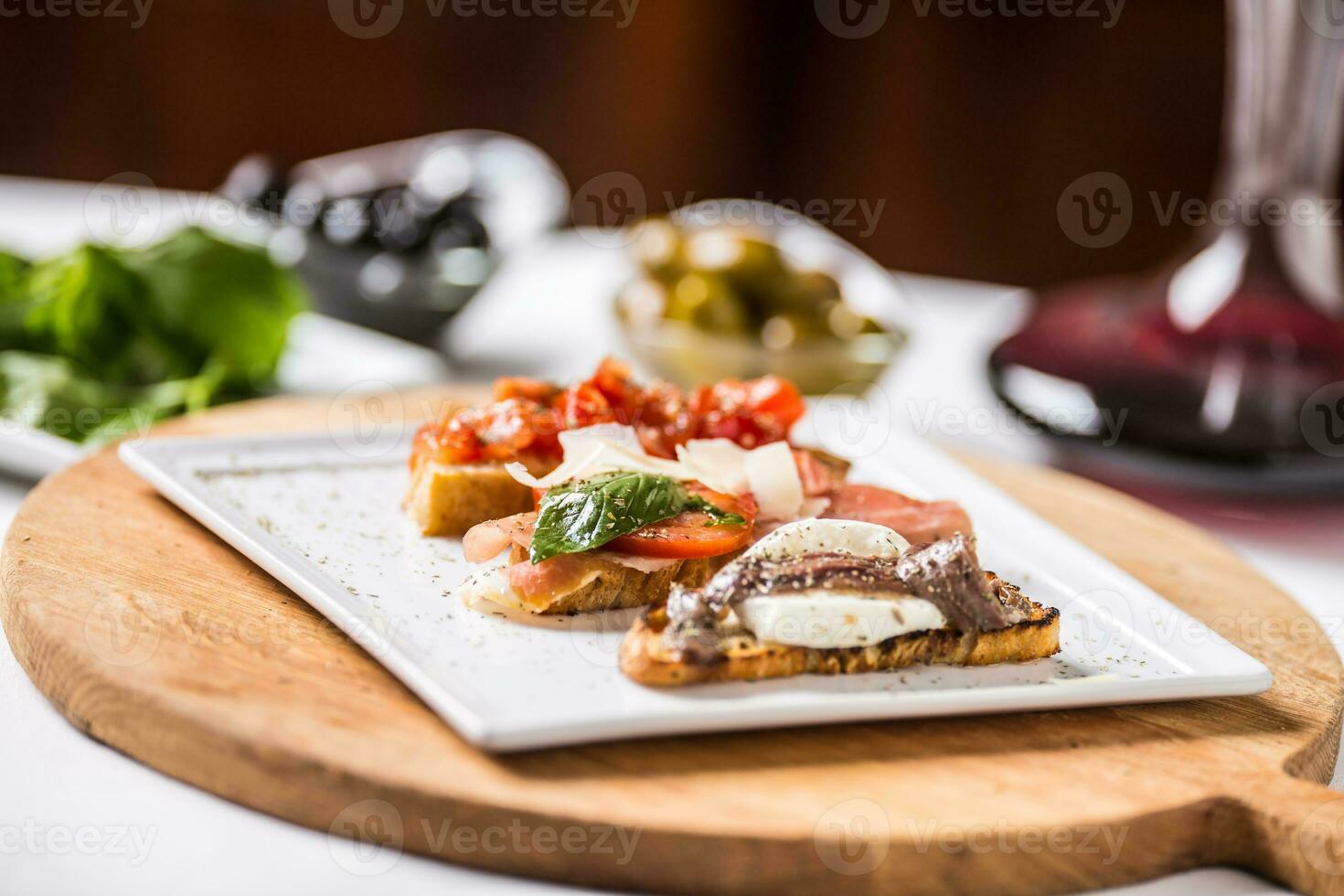 savoureux italien apéritif bruschette avec tomates anchois prosciutto et Mozarella photo