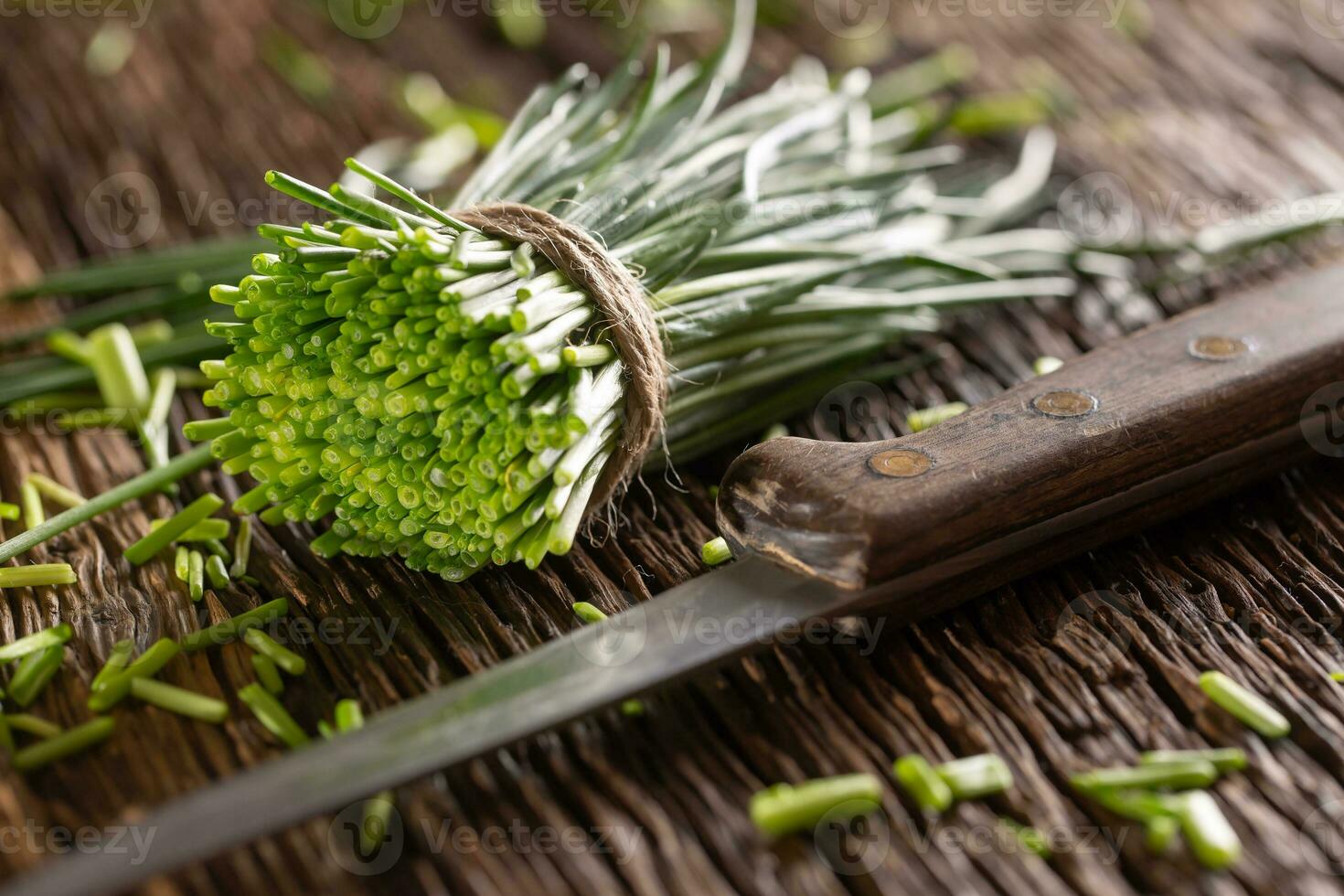 Couper bouquet de ciboulette enveloppé dans une jute ficelle pose sur rustique en bois surface suivant à une couteau photo