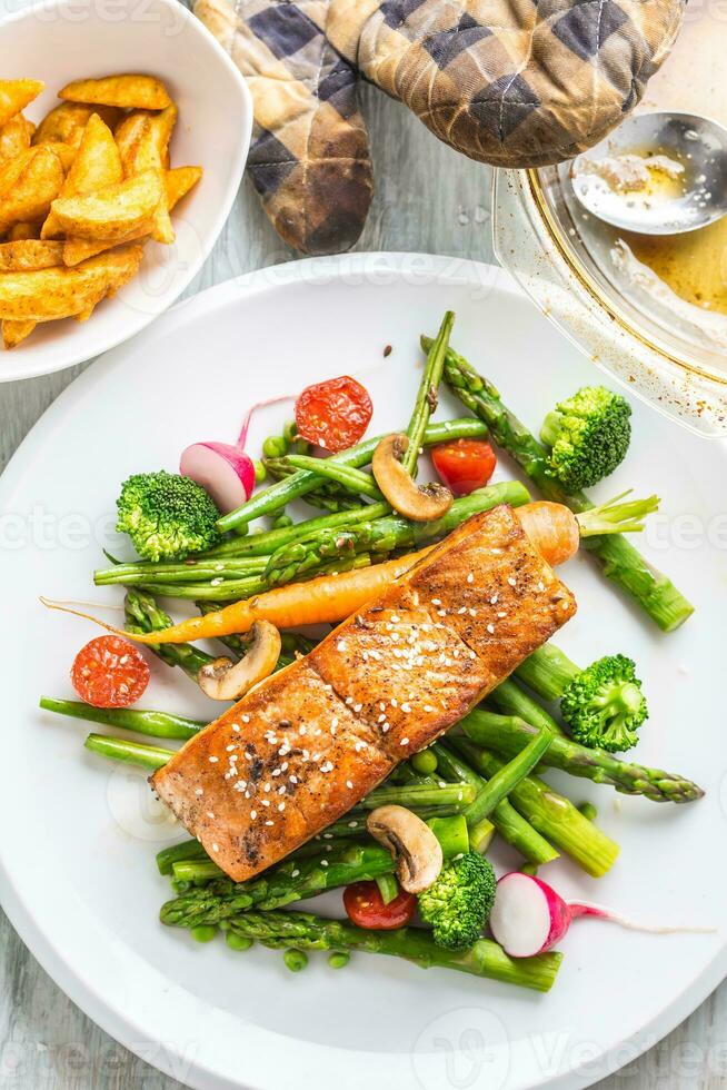 rôti Saumon steak avec asperges brocoli carotte tomates un radis vert des haricots et petits pois. poisson repas avec Frais légume photo