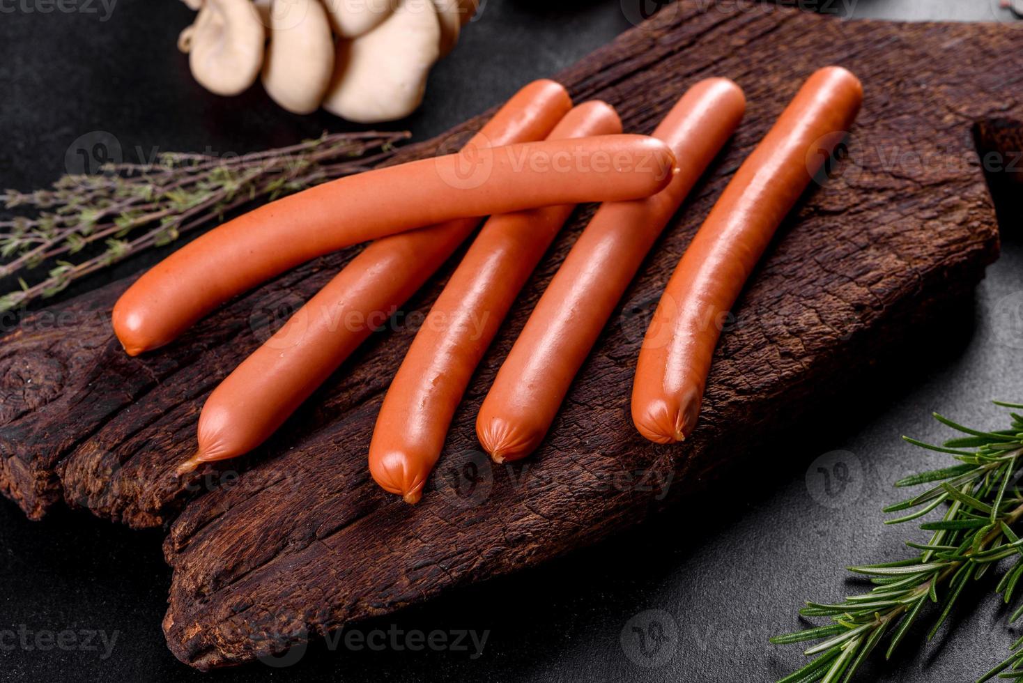 saucisses bouillies sur une planche à découper en bois sur fond de béton foncé photo