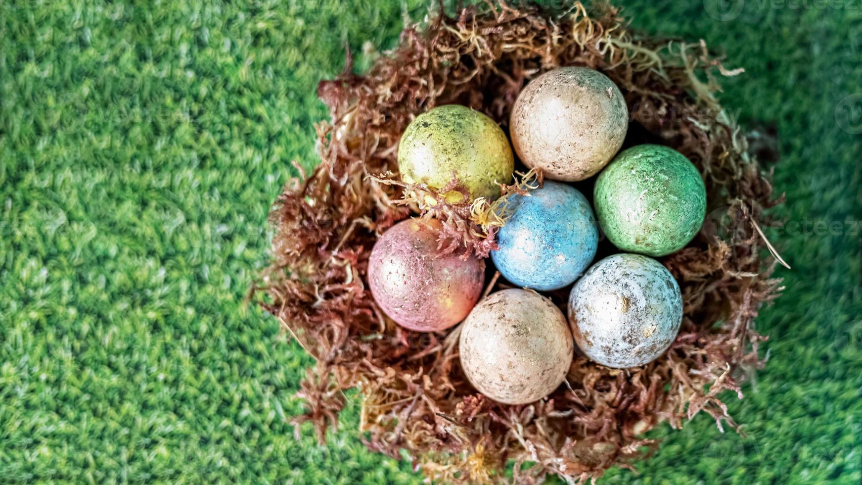 oeufs de pâques dans un nid naturel avec de la mousse sur un fond vert avec une texture d'herbe photo