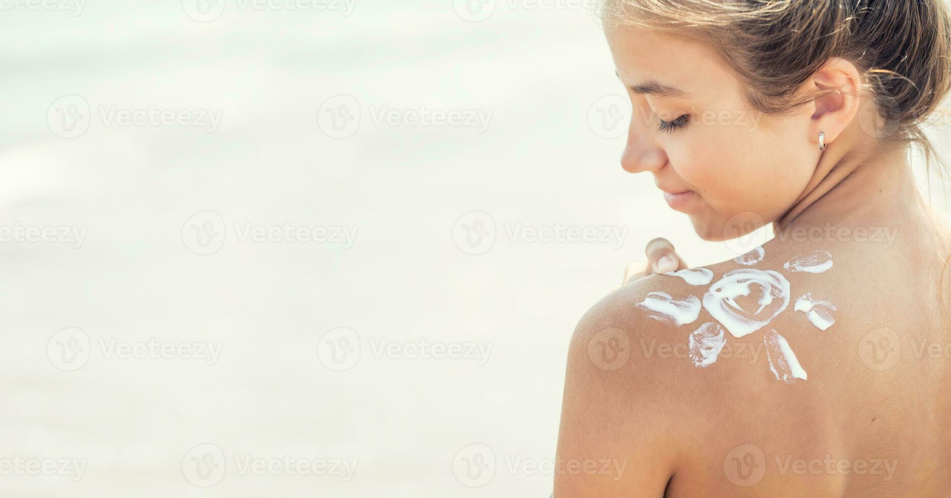 magnifique Jeune fille appliquant crème solaire sur sa épaule sur le plage photo