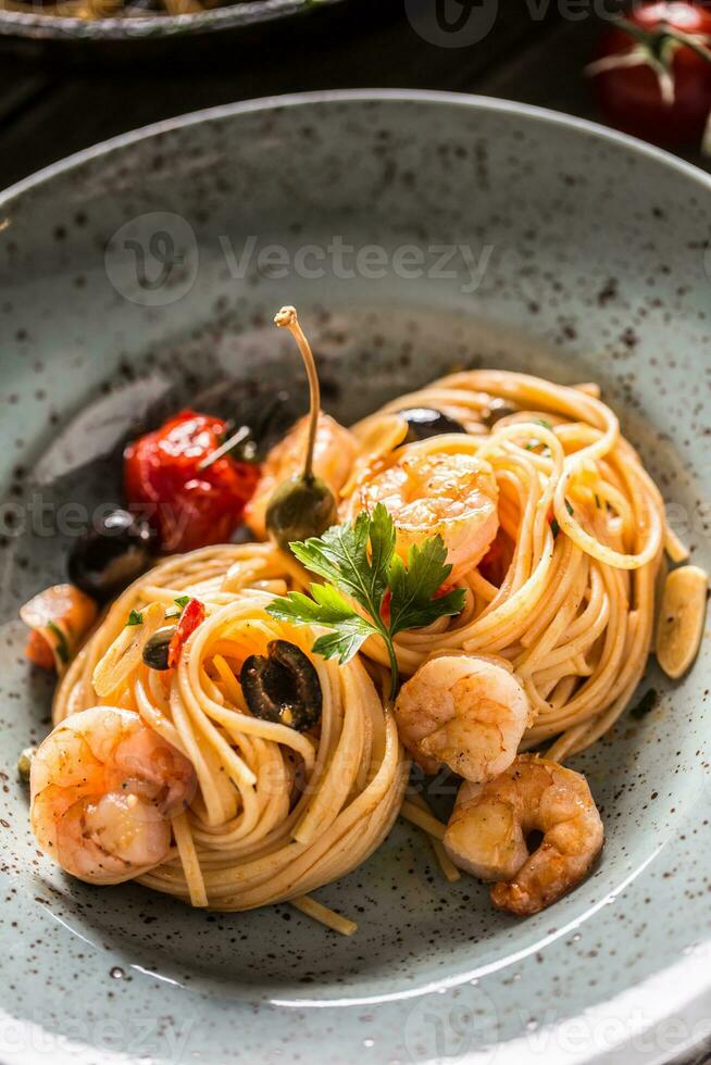 Pâtes spaghetti sur assiette et la poêle avec crevette tomate sauce toates et herbes. italien ou méditerranéen cuisine photo