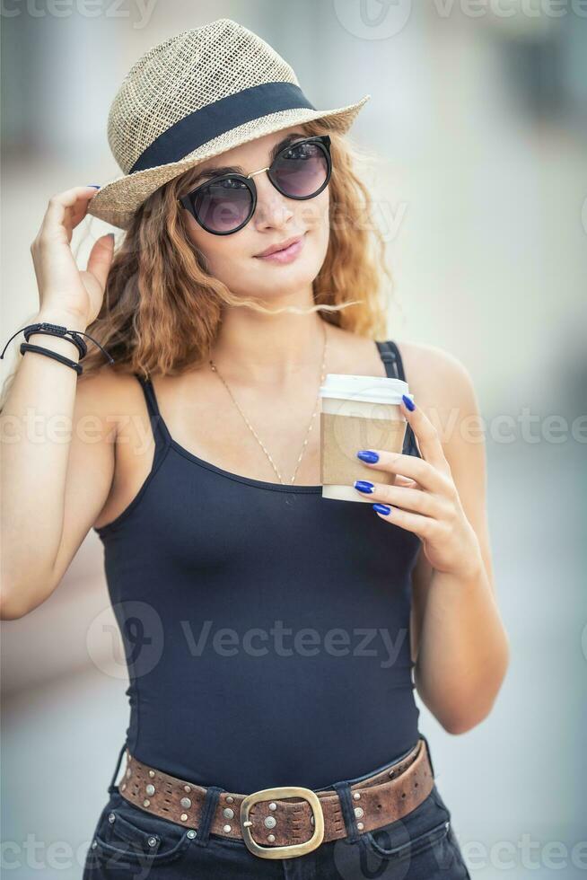Jeune blond femme en buvant café quelque part dans le ville des rues photo