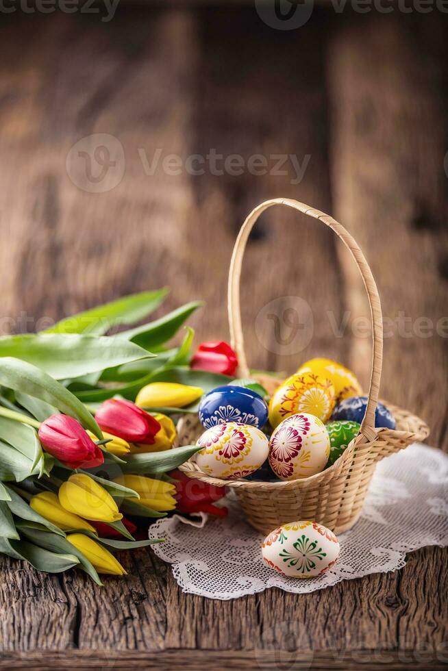 Pâques. main fabriqué peint Pâques des œufs dans panier et printemps tulipes. photo