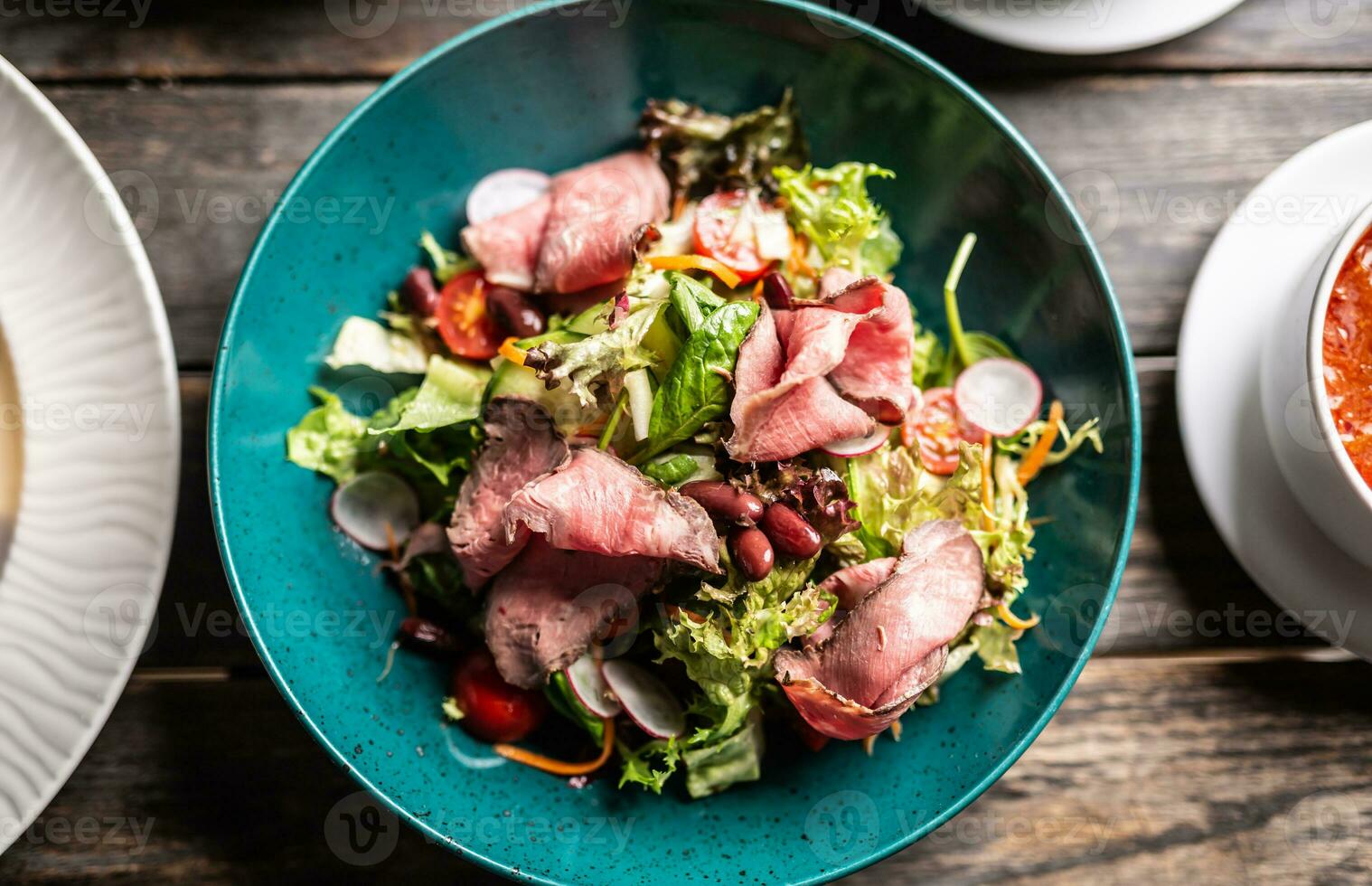 Haut vue de rôti de bœuf avec une coloré salade servi sur une turquiose assiette photo