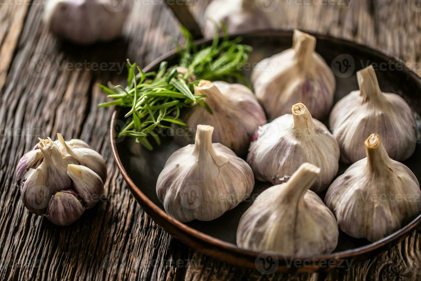 Ail clous de girofle et ampoule dans la poêle avec Frais Romarin sur vieux en bois table photo