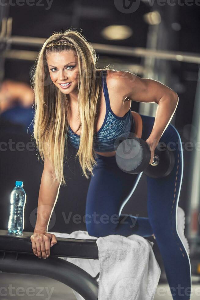 sportif magnifique Jeune femme pratiquant avec haltères dans Gym photo