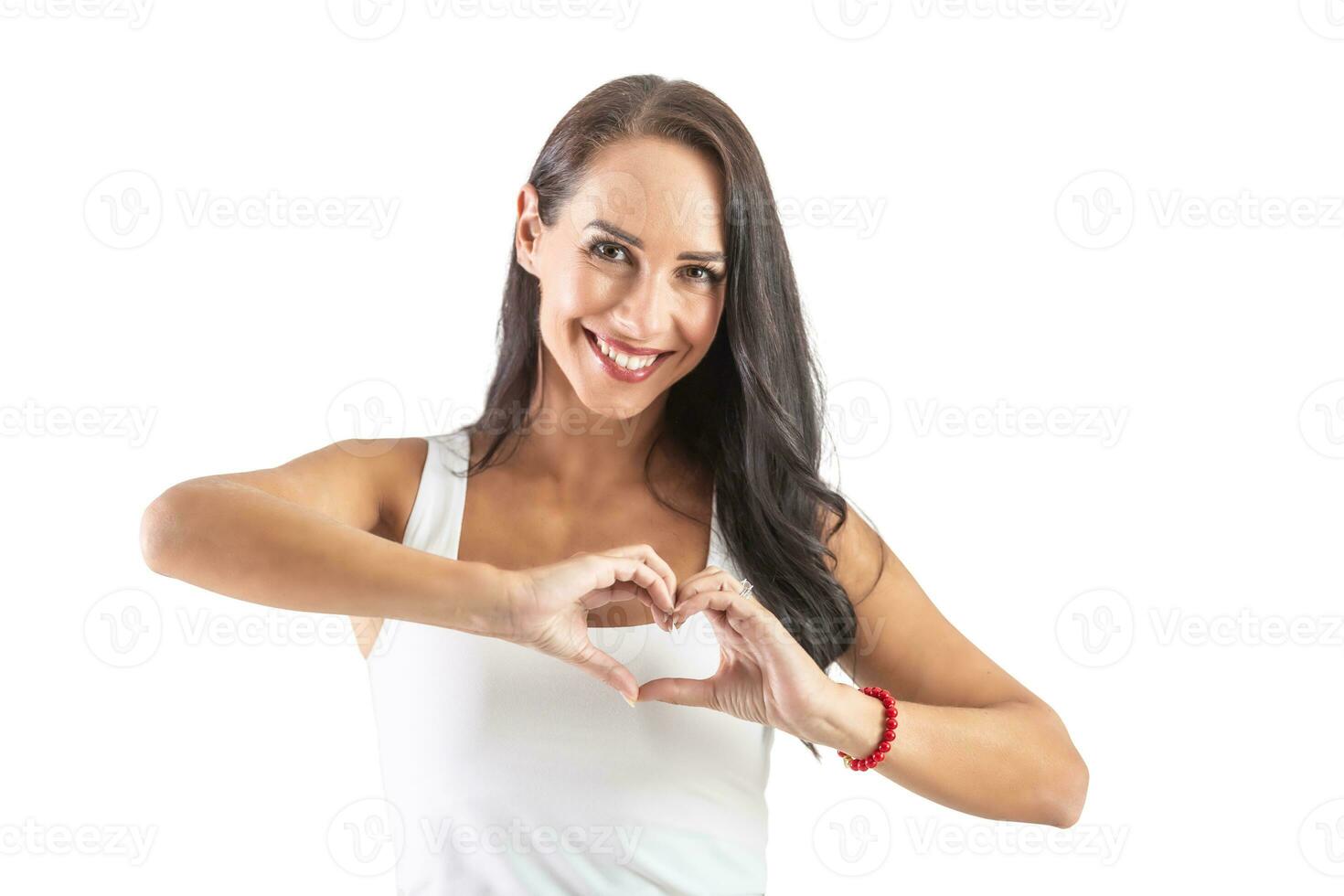 magnifique brunette dans une blanc chemise Faire une cœur signe dans de face de sa poitrine prétendre l'amour et paix à le monde. isolé Contexte photo