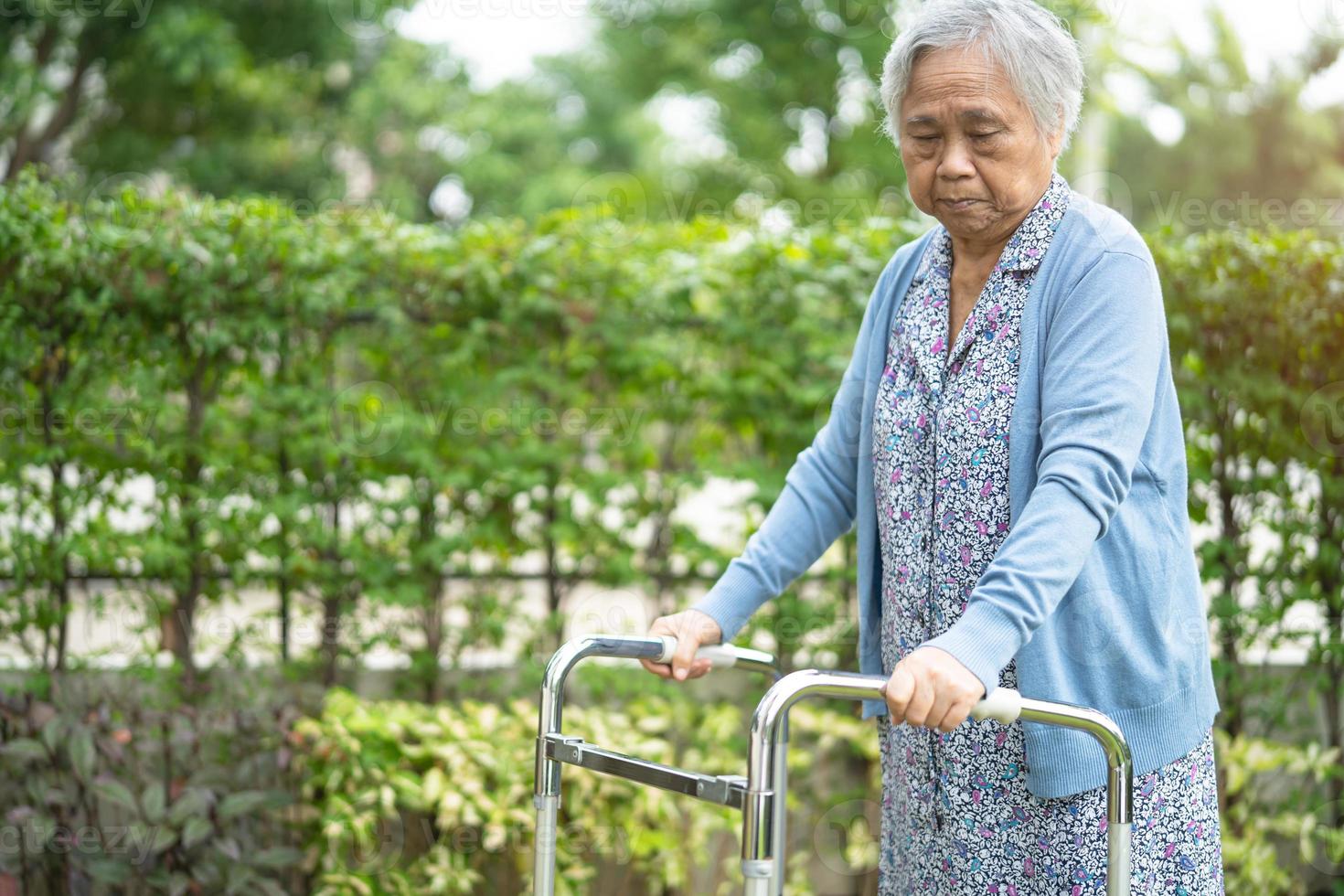 Une vieille dame asiatique âgée ou âgée utilise un marcheur en bonne santé tout en marchant au parc en vacances joyeuses photo