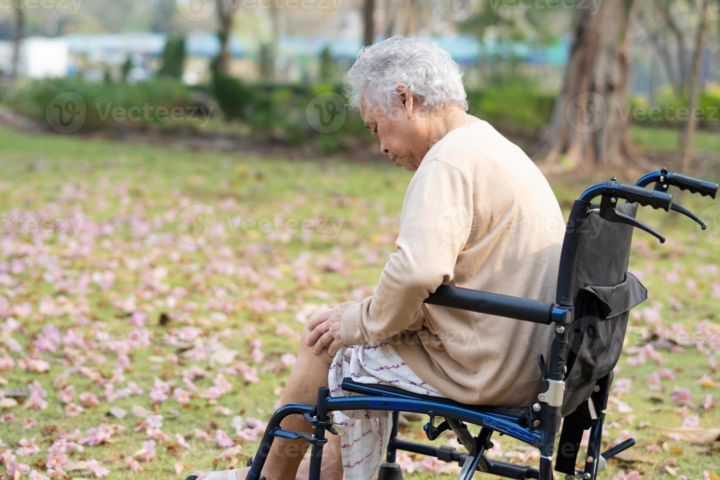 Une patiente asiatique âgée ou âgée, une femme âgée, souffre de son genou sur un fauteuil roulant dans un parc, concept médical solide et sain. photo