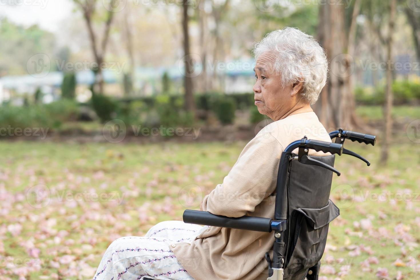 Une patiente asiatique âgée ou âgée, une femme âgée, souffre de son genou sur un fauteuil roulant dans un parc, concept médical solide et sain. photo