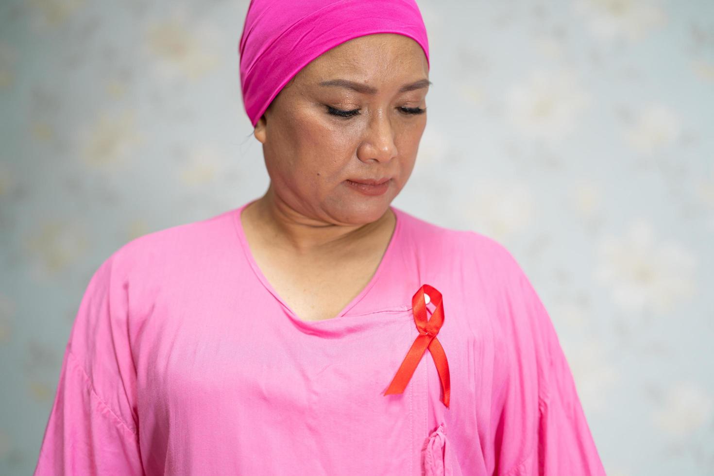 une femme asiatique souffre et inquiète sa poitrine à l'hôpital, symbole de la journée mondiale du cancer du sein. photo