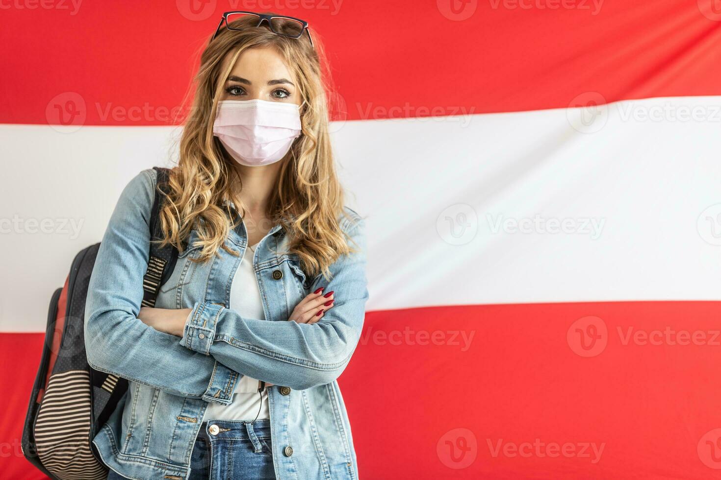 femelle étudiant dans visage masque des stands avec bras franchi dans de face de drapeau de L'Autriche photo