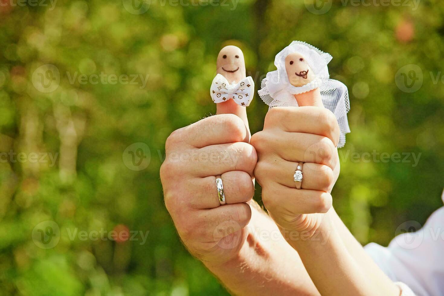 une homme et femme en portant doigt marionnettes avec mariage anneaux photo