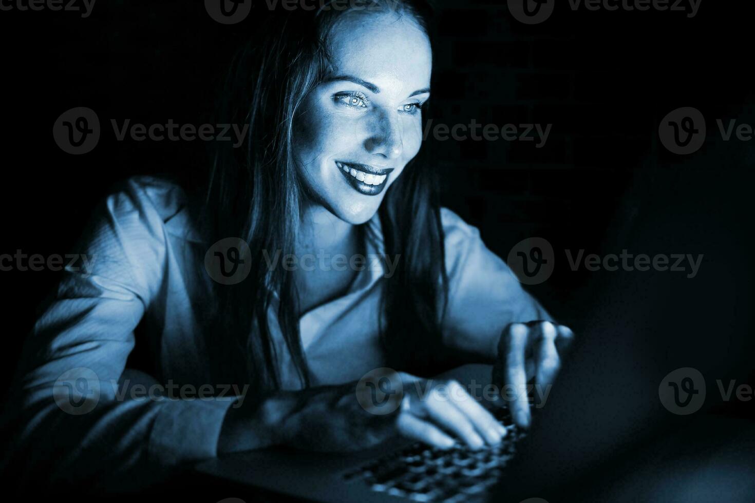 une femme souriant tandis que en utilisant une portable ordinateur photo