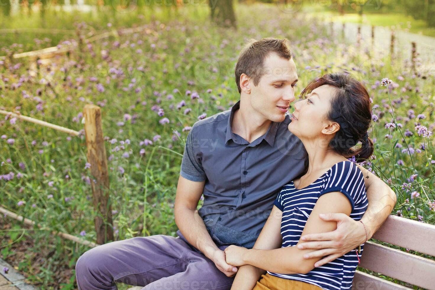 une homme et femme séance sur une banc dans une parc photo