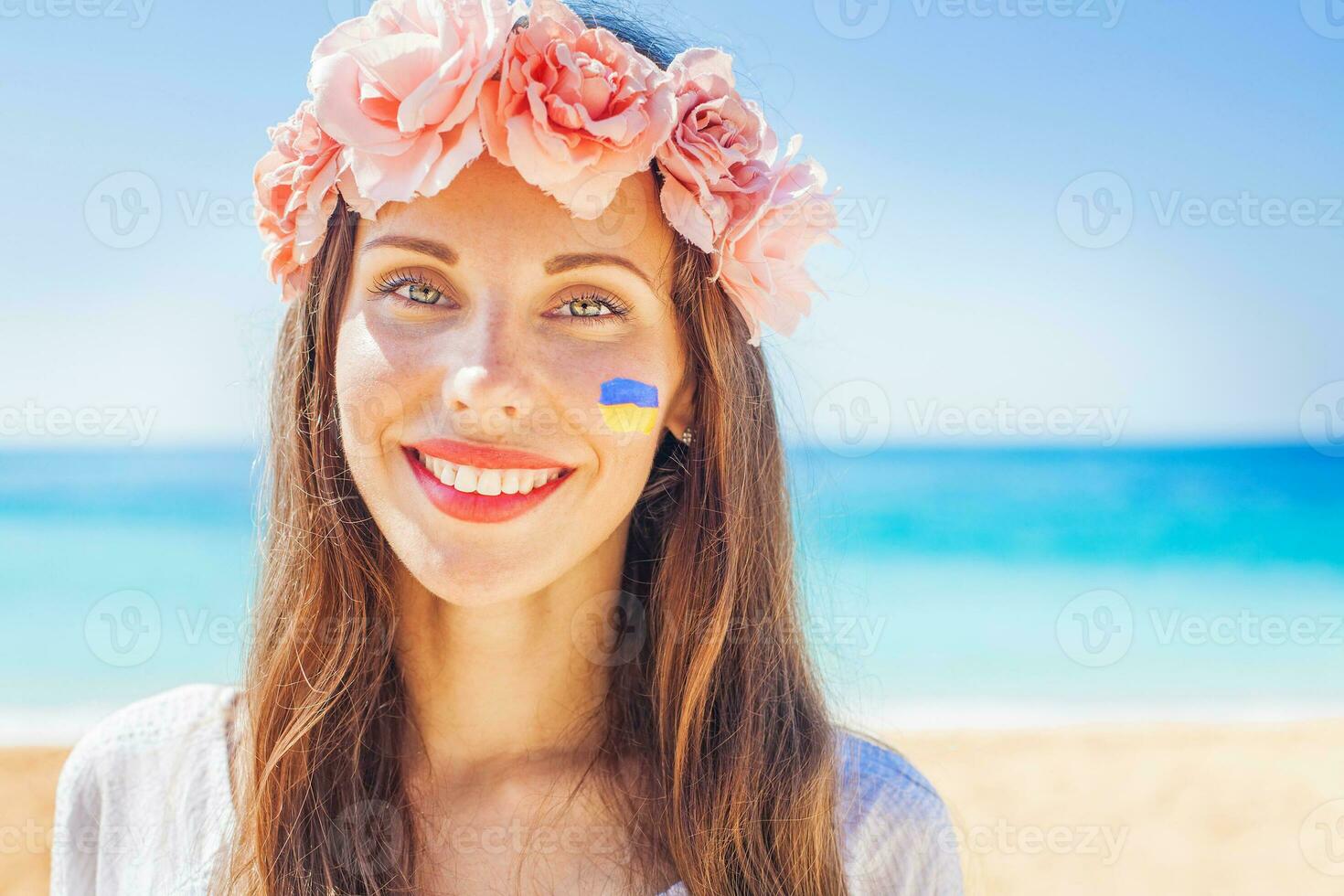 une femme avec fleurs dans sa cheveux et une drapeau peint sur sa visage photo