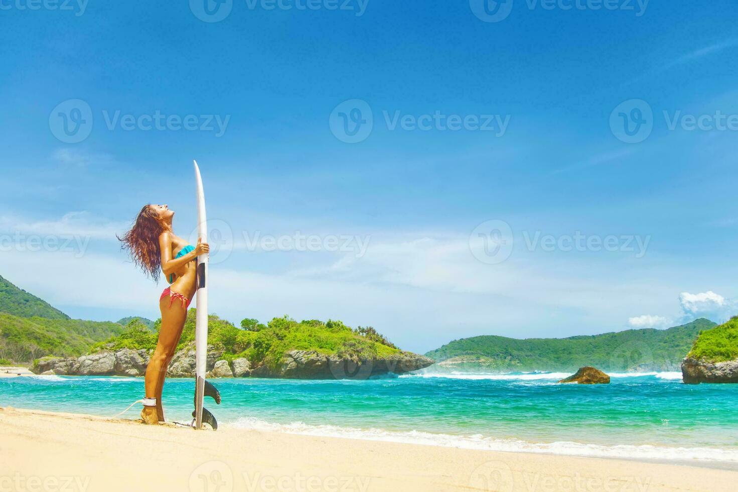 femme dans une maillot de bain repos plus de une le surf sanglier sur une plage dans sumbawa, Indonésie photo