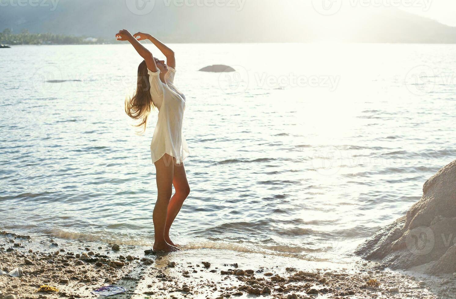 une femme dans une blanc robe permanent sur le plage photo